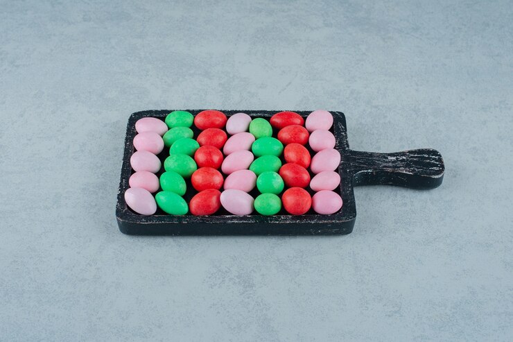 Free Photo a dark wooden board full of round sweet colorful candies on white surface