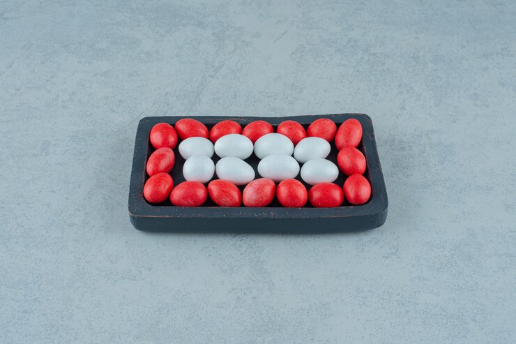 Free Photo a dark wooden board full of round sweet colorful candies on white surface