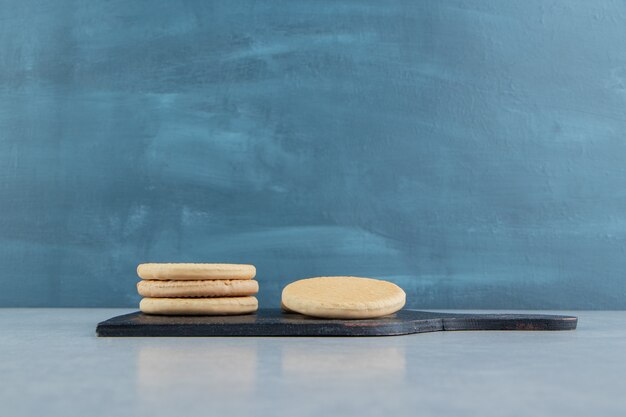 A dark wooden board with sweet round cookies.  