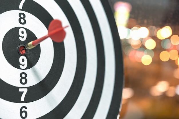 Dart target arrow hitting on bullseye with bokeh background