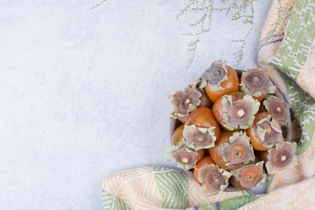 Date plums in a wooden platter on grey background