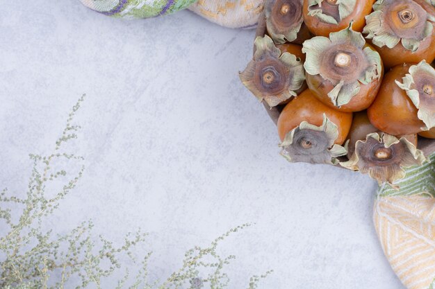 Date plums in a wooden platter on grey background