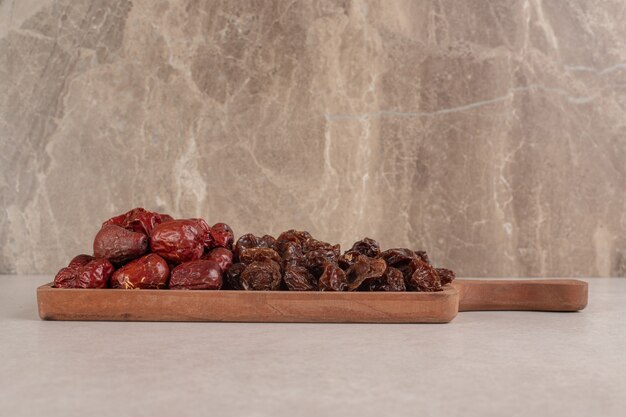 Dates and dry plums on a wooden platter.