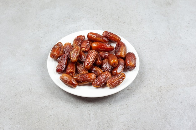 Dates on a white plate on marble background. High quality photo