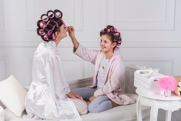 Daughter applying makeup on mothers face 