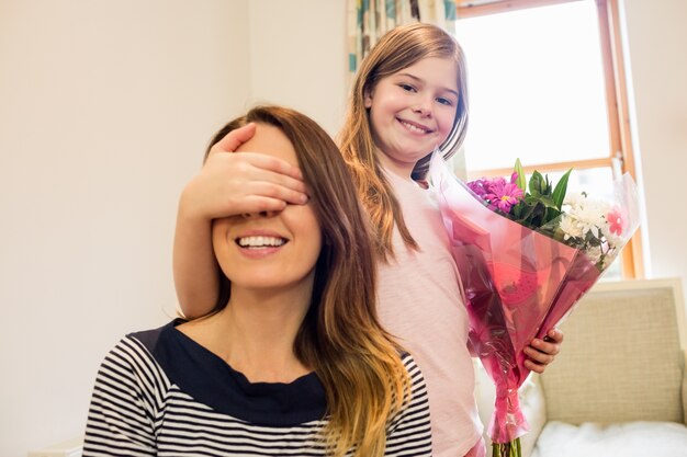 Daughter covering her mother eyes in living room