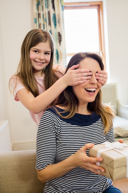 Daughter covering her mother eyes in living room
