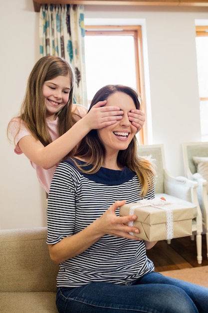 Daughter covering her mother eyes in living room