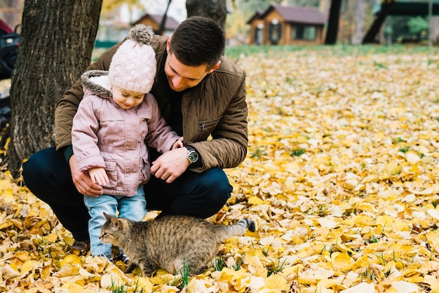 Дочь и папа, глядя на кошку в осеннем парке