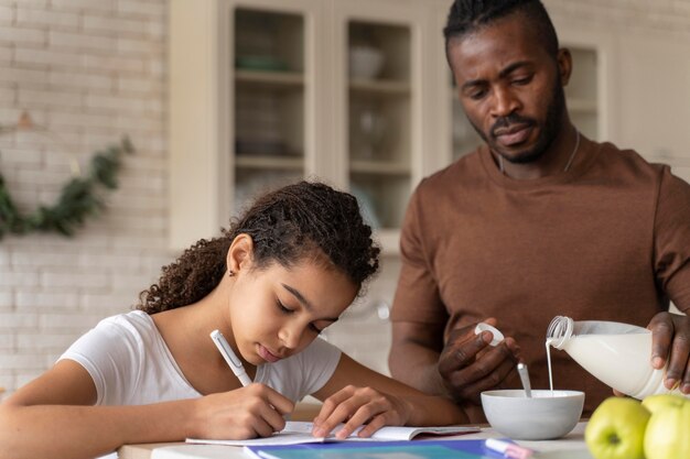 Daughter doing homework next to her father in the kitchen