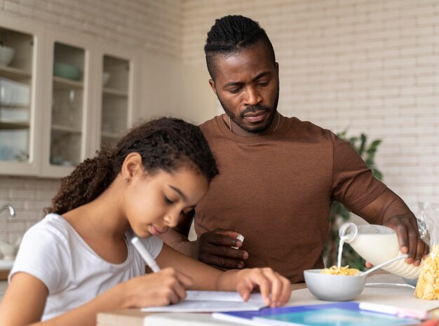 Daughter doing homework next to her father in the kitchen