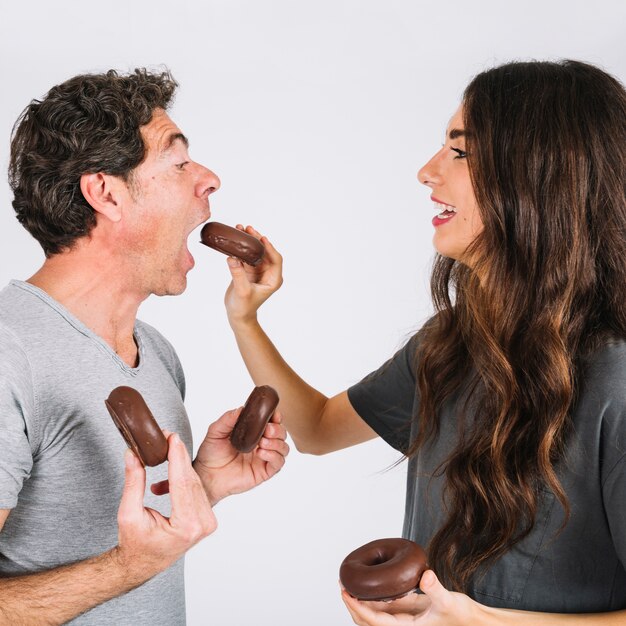 Daughter feeding father with donuts