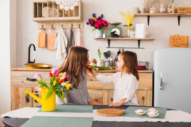 Daughter feeding mother with cupcake