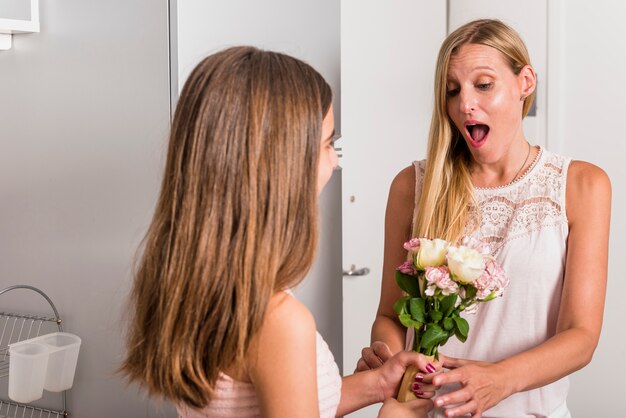 Daughter giving flowers to amazed mother