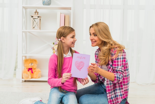 Daughter giving greeting card to mother