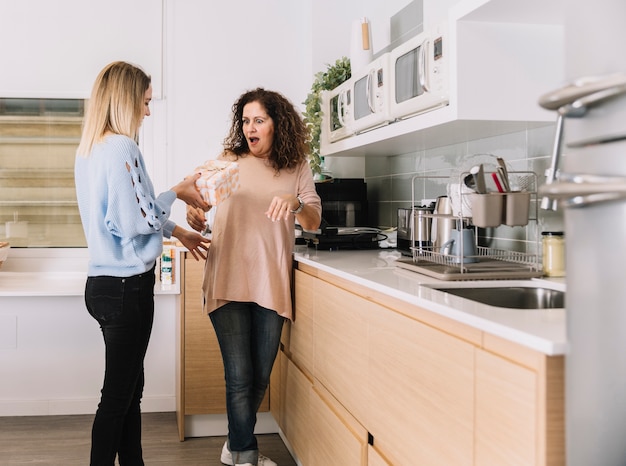 Daughter giving present to mother in kitchen