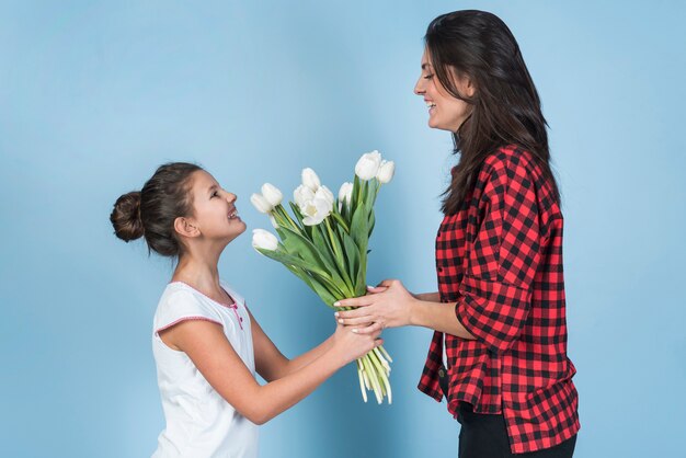 Daughter giving white tulips to mother 