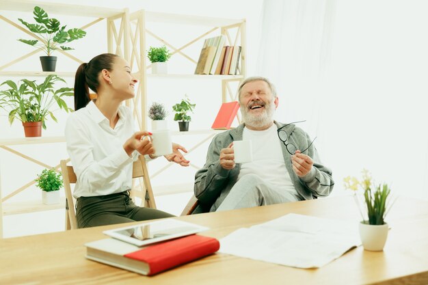 A daughter or granddaughter spends time with the grandfather or senior man drinking tea