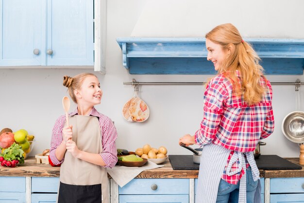 Daughter and her mother cooking food in the kitchen