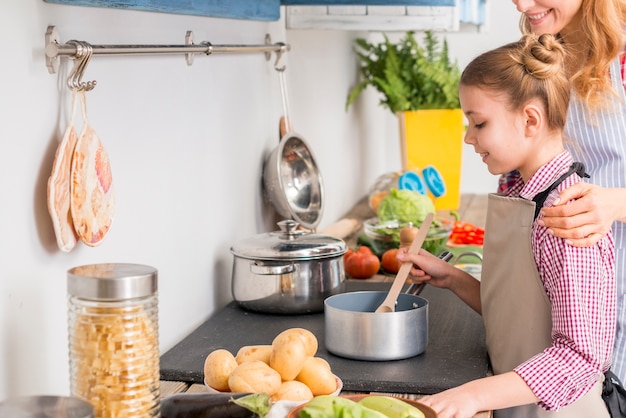 Figlia e sua madre che cucinano zuppa in cucina