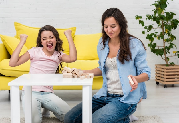 Figlia e sua madre che giocano insieme a una torre di legno