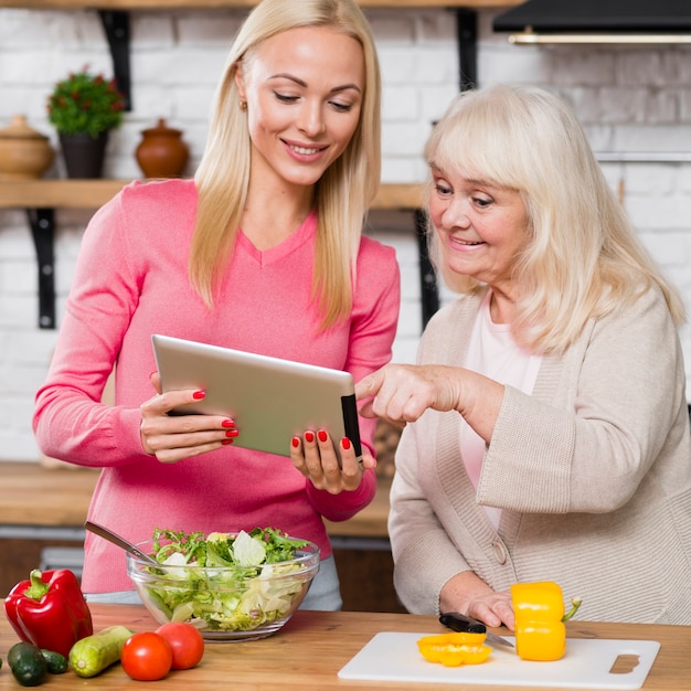 Daughter holding digital tablet and mother scrolling