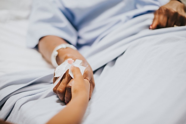 Daughter holding her mothers hand in the hospital