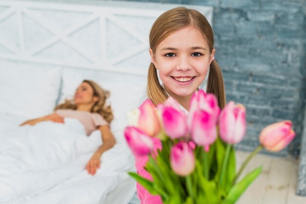 Daughter holding tulips for sleeping mother 