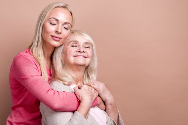 Foto gratuita figlia che abbraccia sua madre con gli occhi chiusi e lo spazio della copia