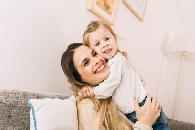 Daughter hugging mother on sofa