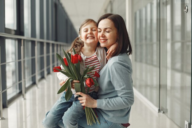 A daughter is giving mother a bunch of red tulips