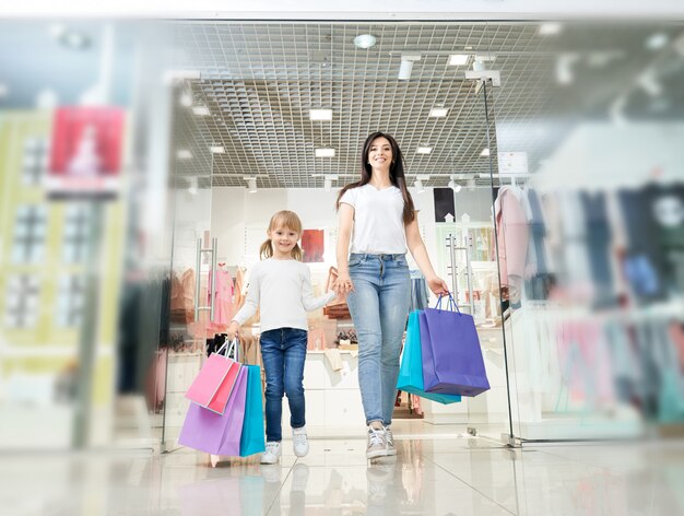Дочь держит руку матери и выходит из магазина