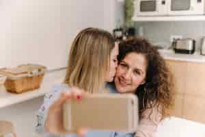 Foto gratuita figlia che bacia mamma mentre si fa selfie