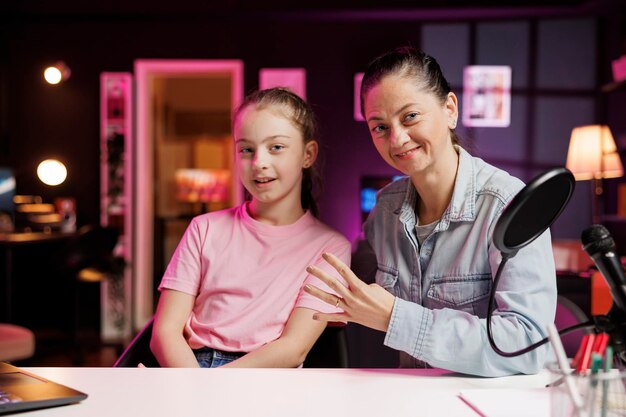 Free photo daughter and mother doing content creation in pink neon studio