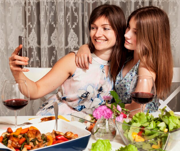 Daughter and mother taking selfie at dinner table