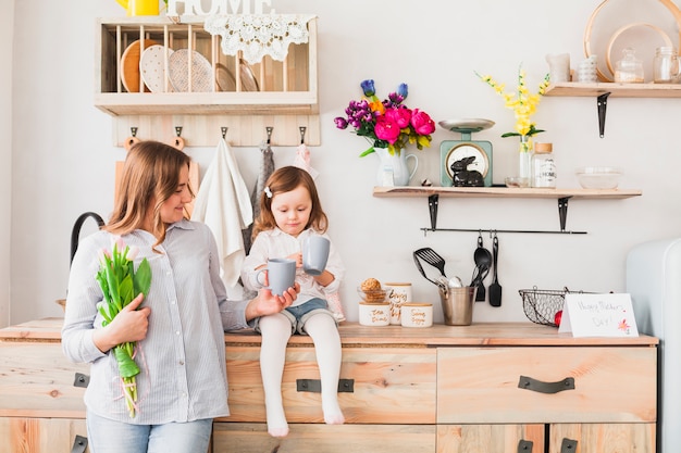 Daughter and mother with flowers drinking tea