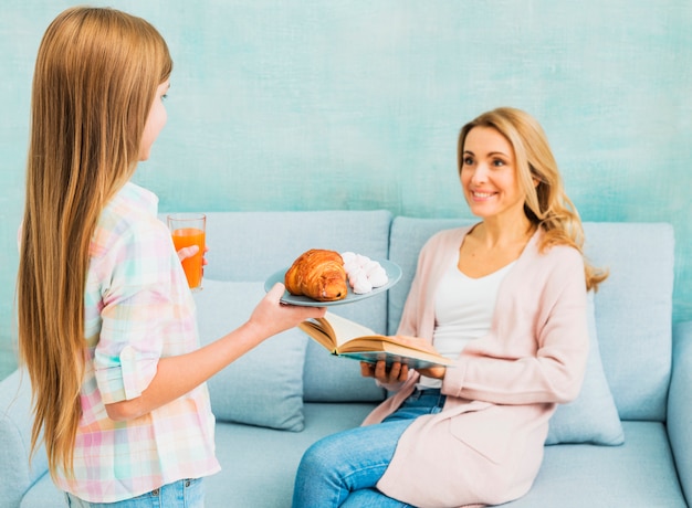 Free photo daughter presenting mother`s day breakfast for mom