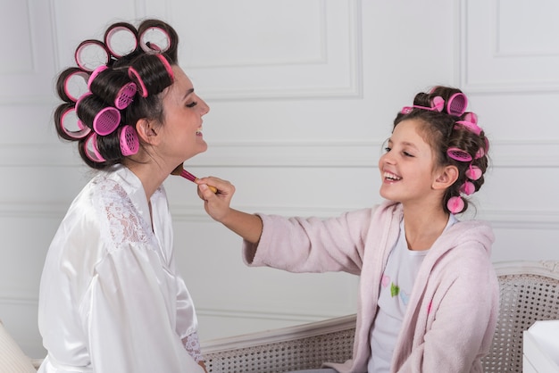 Free photo daughter putting powder on mothers neck