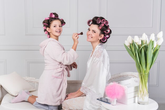 Daughter putting powder with brush on mothers face