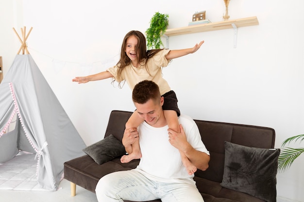 Daughter sitting on her father's shoulders at home