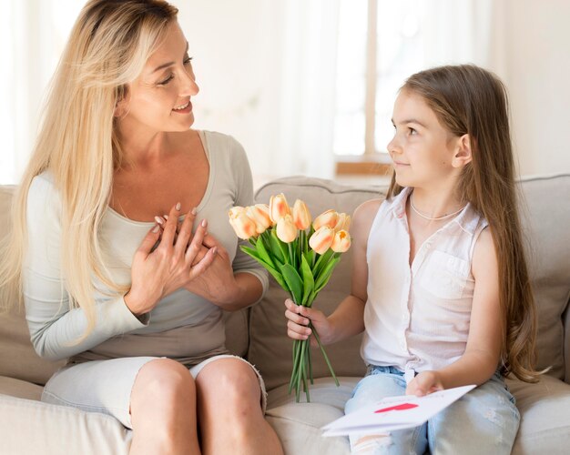 Daughter surprising mother with bouquet of flowers