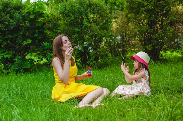 Daughter taking a picture of her mother while making bubbles