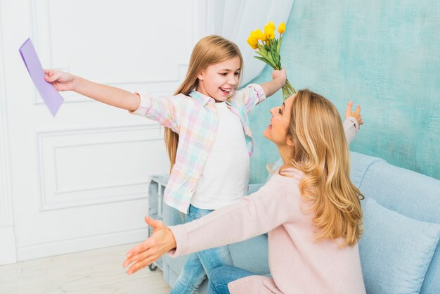 Дочь с подарками цветет и открытка обнимает маму