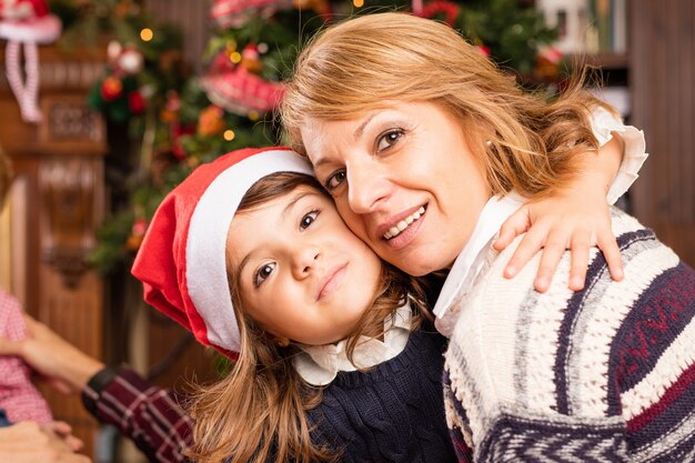 Daughter with santa hat hugging her mother