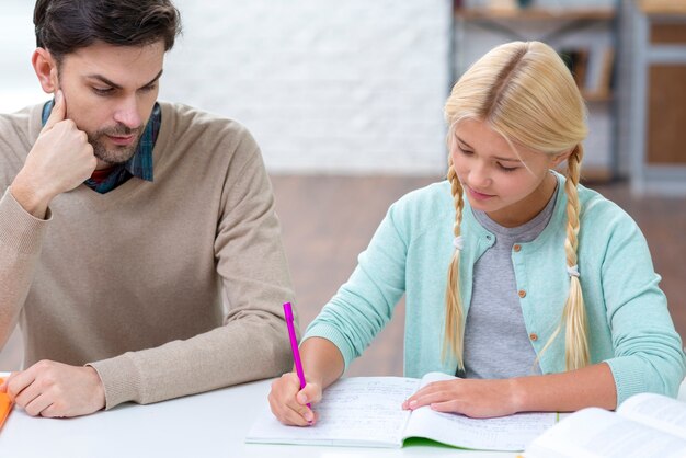 Daughter writing and father is looking