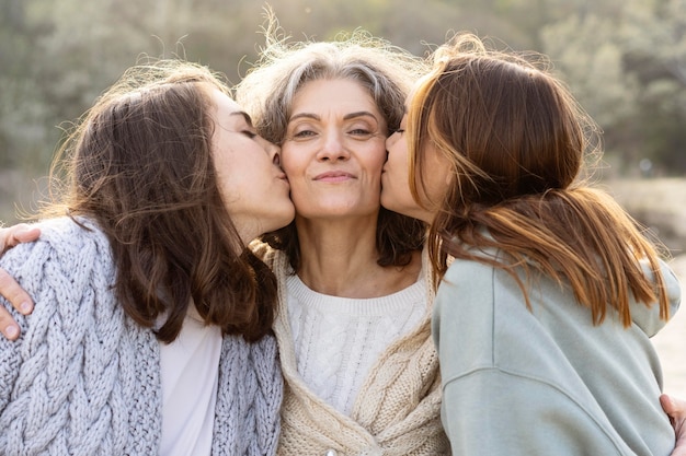 Daughters kissing mother outdoors