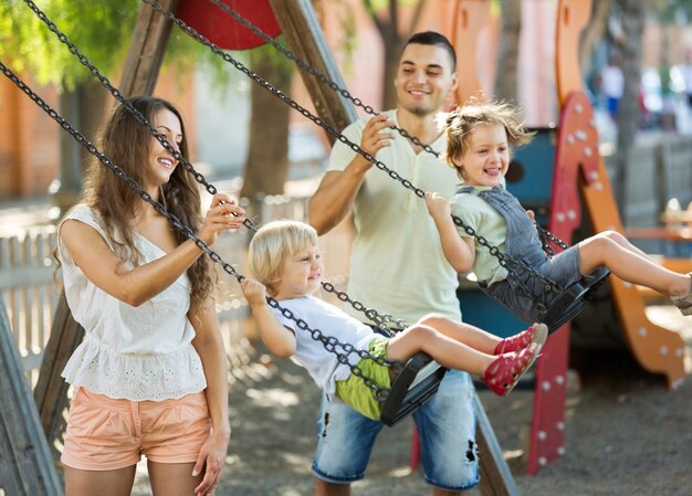 Daughters on swings with parents