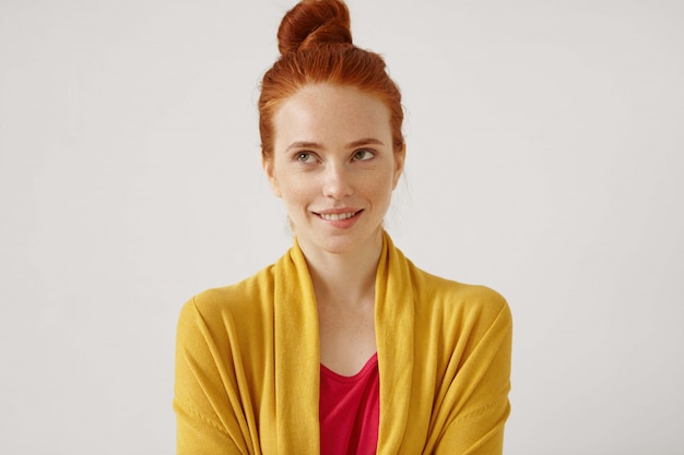 Daydreaming, ideas, thoughts and anticipation concept. Picture of cute woman wearing her ginger har in bun looking up and biting her lips while dreaming about something pleasant and nice