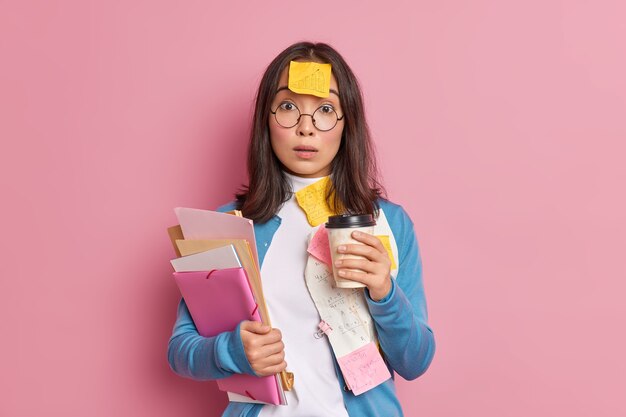 Deadline and overwork concept. Stunned Asian female office worker drinks coffee to go.