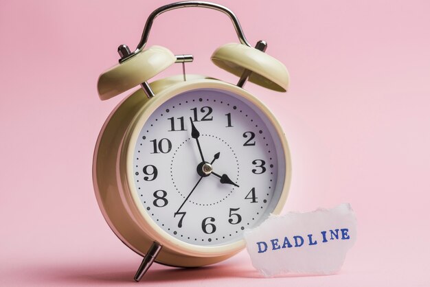 Deadline text on torn paper near the yellow clock against pink background